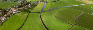 Amsterdam yakınlarındaki küçük geleneksel Ransdorp köyünü çevreleyen hendek ve siperlerden oluşan sulama altyapısı ile desenli tarımsal yeşil çayır alanlarının tepeden aşağı hava manzarası