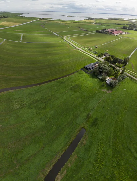 Aerial view of the agrarian green pasture fields with its irrigation infrastructure of ditches and trenches surrounding the small traditional village of Ransdorp near Amsterdam