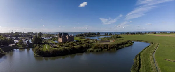 Aerial panoramic view of the island with the Muiderslot castle in Muiden near Amsterdam and its lush gardens at the IJsselmeer with surrounding water entrenchment at sunset