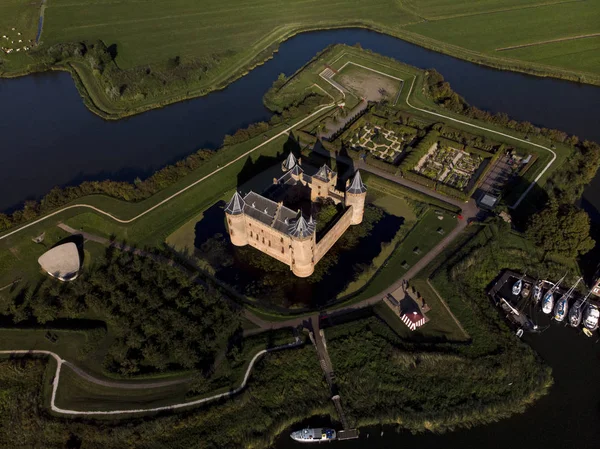 Amsterdam yakınlarındaki Muiden 'daki Muiderslot şatosu ve Ijsselmeer' deki yemyeşil bahçeleri ile birlikte gün batımında etrafındaki su siperleri ile adanın panoramik manzarası.