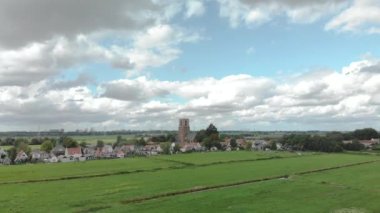 Aerial approach of the village of Ransdorp with its agrarian surroundings just outside of Amsterdam in The Netherlands against a blue sky with clouds