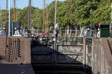 Muiden, Hollanda - 1 Eylül 2019: Liman bölgesi ve iskele kapısı Amsterdam yakınlarındaki tarihi stratejik su yolu noktasında arka planda Muiderslot kalesi ile kesişiyor.