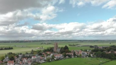 Tarımsal çevresiyle Ransdorp köyünü ve Hollanda 'daki Amsterdam şehrini, bulutlu mavi bir gökyüzüne karşı gösteren havadan eğim yükseliyor.