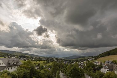 Almanya 'nın Sauerland kentindeki kış sporları bölgesindeki Grafschaft adlı dağlık spa köyünün günbatımı boyunca renkli bir gökyüzü ile panoramik manzarası