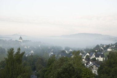 Sauerland kış sporları bölgesinde Grafschaft dağlık kaplıca köyü üzerinde düşük asılı sabah sis, Manastır açıkça sis dışında yapışmasını ile Almanya