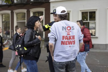 Lahey, Hollanda - 17 Eylül 2019: Den Haag'daki Prinsjesdag'ta sahte haber le aynı ifadelere sahip tişörtlü protestocunun polis tarafından ayrılması isteniyor