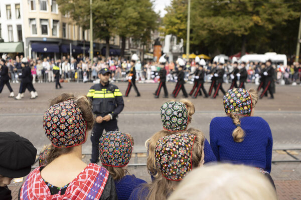 Гаага, Нидерланды - 17 сентября 2019 года: Молодые девушки в традиционной одежде смотрят парад и ждут голландского короля и королеву, проходящих в золотом автобусе на Принсьесдаге
