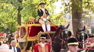 Kral Willem-Alexander ve Hollanda kraliyet ailesinden Kraliçe Maxima at ve at arabası yla geçerek Temsilciler Meclisi'nden Noordeinde Sarayı'na giden yol boyunca kalabalığa el sallıyorlar.
