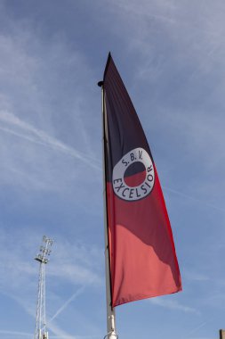 Rotterdam, Hollanda - 20 Eylül 2019: Hollanda futbol kulübü Excelsior 'un bayrağı rüzgarda dalgalanan mavi gökyüzüne karşı arka planda stadyumun aydınlatma koluyla