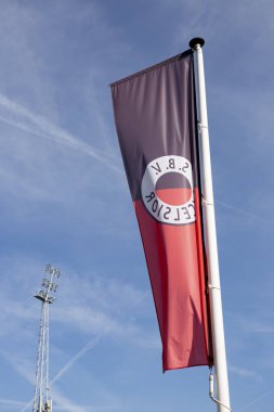 Rotterdam, Hollanda - 20 Eylül 2019: Hollanda futbol kulübü Excelsior 'un bayrağı rüzgarda dalgalanan mavi gökyüzüne karşı arka planda stadyumun aydınlatma koluyla