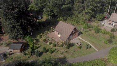 Teraslı bir eğlence parkındaki yazlık evin havadan yaklaşımı ve ön planda bahçe tasarımı.