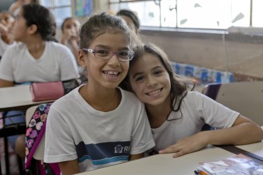 Rio de Janeiro, Brezilya - 2 Temmuz 2015: Okul üniformalı kızlar kameraya bakıp gülümsüyor ve sınıfın odak noktasından uzaklaşıyorlar.