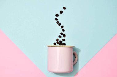 Renkli arka planda kahve çekirdekli pembe bir kupa. Moda pastel renklerinde düz bir fotoğraf.