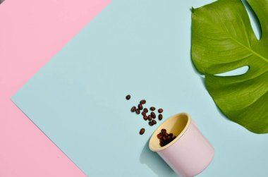 Renkli arka planda kahve çekirdekli pembe bir kupa. Moda pastel renklerinde düz bir fotoğraf.