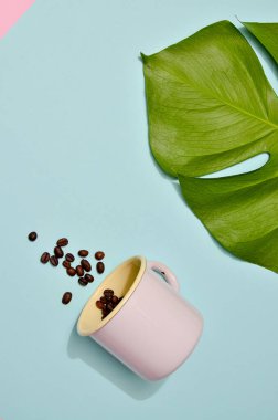 Renkli arka planda kahve çekirdekli pembe bir kupa. Moda pastel renklerinde düz bir fotoğraf.