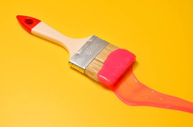 Shot of a brush with pink sticky slime on yellow background. Minimalism in photography, concept creative picture. Painting tool clipart