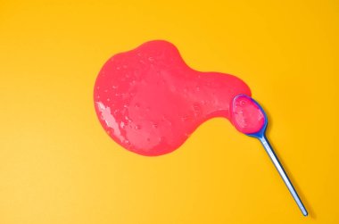 Sarı arka planda pembe yapışkan sümüklü klasik mavi kaşık. Fotoğrafçılıkta minimalizm, konsept yaratıcı resim. Boyama aracı