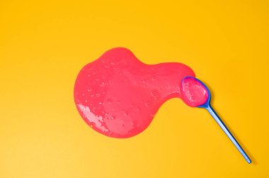 Sarı arka planda pembe yapışkan sümüklü klasik mavi kaşık. Fotoğrafçılıkta minimalizm, konsept yaratıcı resim. Boyama aracı