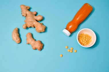 Farklı koşullarda zencefil: taze, kuru kök, haplar ve pastel mavi arka planda kesilmiş bitki. Düz Yat, mesaj için boşluk. Korunma olarak sağlıklı desenler, koronavirüstür.