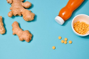 Farklı koşullarda zencefil: taze, kuru kök, haplar ve pastel mavi arka planda kesilmiş bitki. Düz Yat, mesaj için boşluk. Korunma olarak sağlıklı desenler, koronavirüstür.
