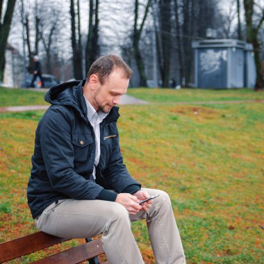 Mavi paltolu, bej pantolonlu yakışıklı bir işadamının gülümsemesi ve telefonda konuşması.