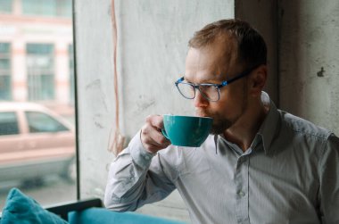 Yakışıklı işadamı gülümseyip, kahve içiyor. Masadaki kafede oturan adam.