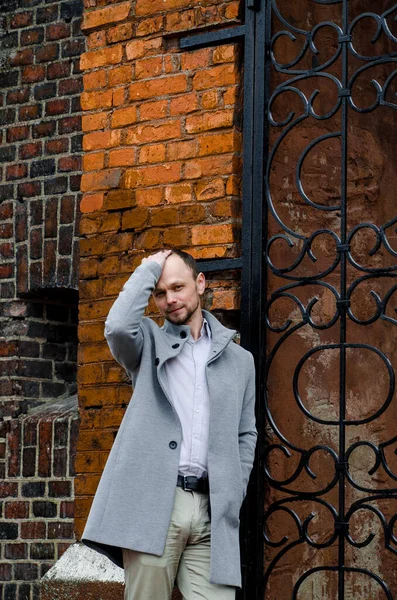 stock image Handsome businessman freelancer in grey coat and biege trousers smiles and walking down the sidewalk