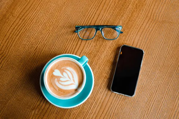 Vasos azules, teléfono móvil y taza de café azul en la mesa de madera. Patrón empresarial —  Fotos de Stock