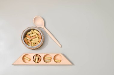 Kapsüllerdeki bitkiler ahşap kasede pastel bej arka planda. Yüz ve vücut bakımı için güzellik ürünleri