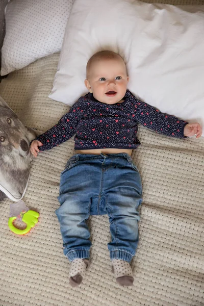 Surpreendido bebê menina deitada na cama e olhando para cima — Fotografia de Stock