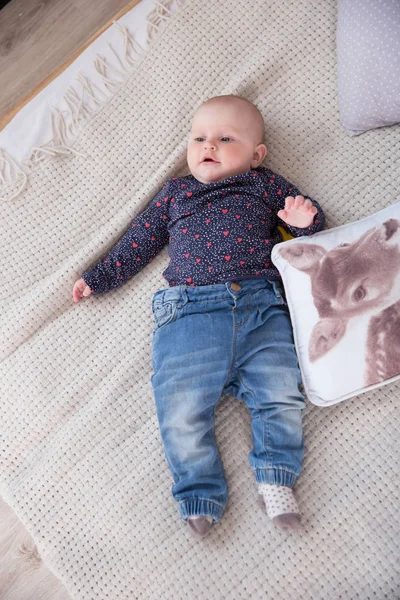 Sério bebê menina deitada na cama e olhando para cima — Fotografia de Stock