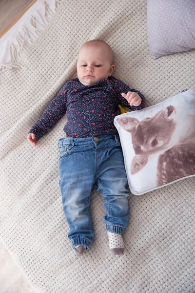Sério bebê menina deitada na cama e olhando para cima — Fotografia de Stock