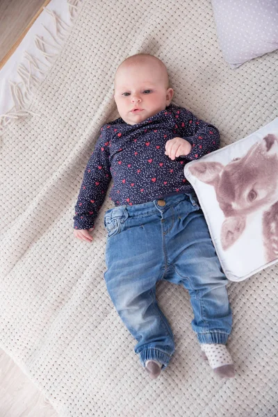 Sério bebê menina deitada na cama e olhando para cima — Fotografia de Stock