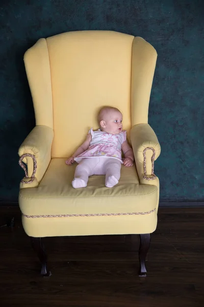 Bebê menina sentada em poltrona grande no estúdio — Fotografia de Stock