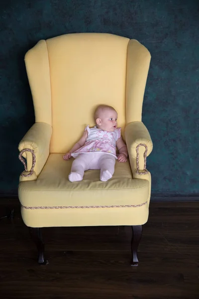 Bebé niña sentada en un sillón grande en el estudio — Foto de Stock