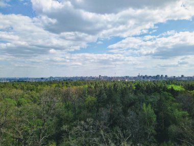 Güneşli bir günde yeşil bahar ormanı ve şehir manzarasının güzel panoramik manzarası