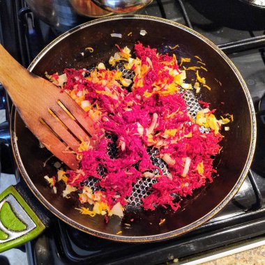 Mutfak spatulası, dilimlenmiş soğan, havuç ve pancar ile mutfak sobası manzarası.