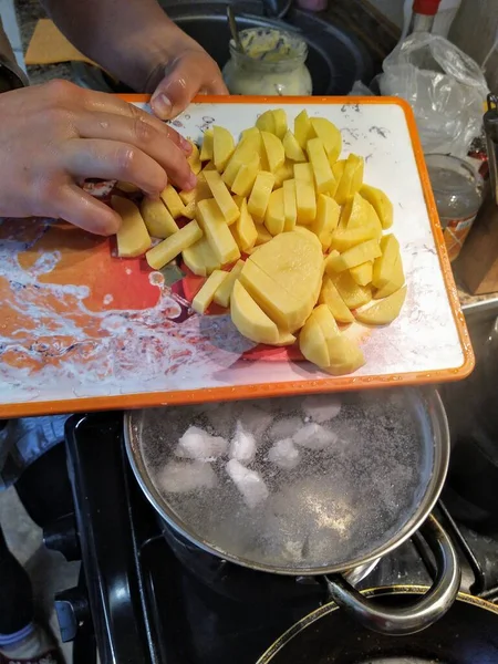切り取られた女性のビューは キッチンストーブの上に鍋にスライスしたジャガイモをスロー — ストック写真