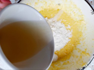 Kişinin kısmi görüntüsü hamurla oynamak için limon suyu ve kek pişirmek için un döküyor.