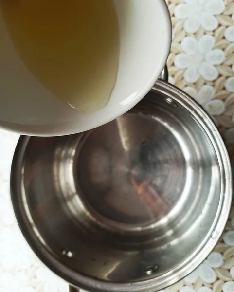 テーブルクロスでテーブルの上にカップから鍋にレモン汁を絞るのトップビュー — ストック写真