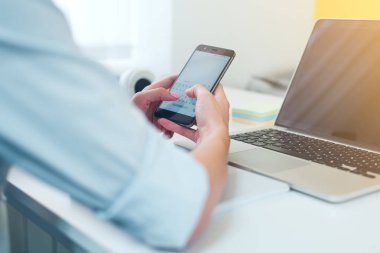 Modern akıllı telefon ile bilgisayar, onun cep telefonundan kısa mesaj yazarak işkadını ofisinde çalışırken kullanarak eller Close-up