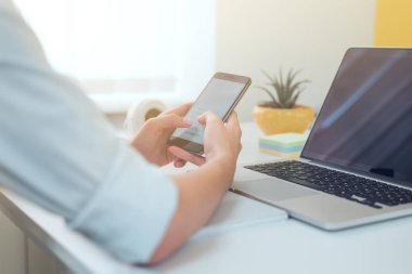 Modern akıllı telefon ile bilgisayar, onun cep telefonundan kısa mesaj yazarak işkadını ofisinde çalışırken kullanarak eller Close-up