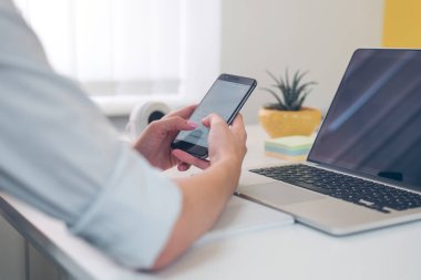 Modern akıllı telefon ile bilgisayar, onun cep telefonundan kısa mesaj yazarak işkadını ofisinde çalışırken kullanarak eller Close-up