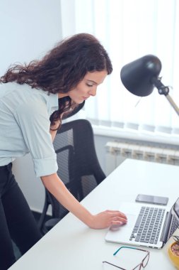 Mesaj yazma, bir dizüstü bilgisayar kullanarak ofisinde, duran güzel meşgul iş kadını,