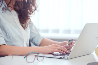 Kredi kartı tutan ve dizüstü bilgisayar kullanan eller. İnternetten alışveriş
