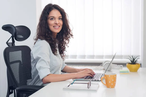 Young pretty business woman with notebook in the office, looking to camera