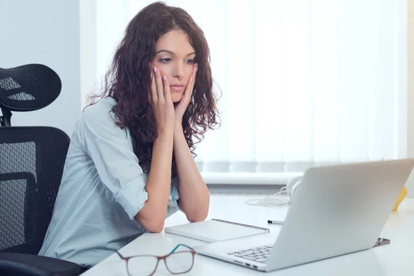 Surprised woman working on computer while sitting at her working place, copy space