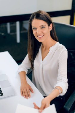 Genç işkadını kapalı, otururken belge veren gülümseyen