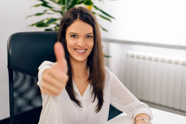 Smiling successful woman giving a thumbs up