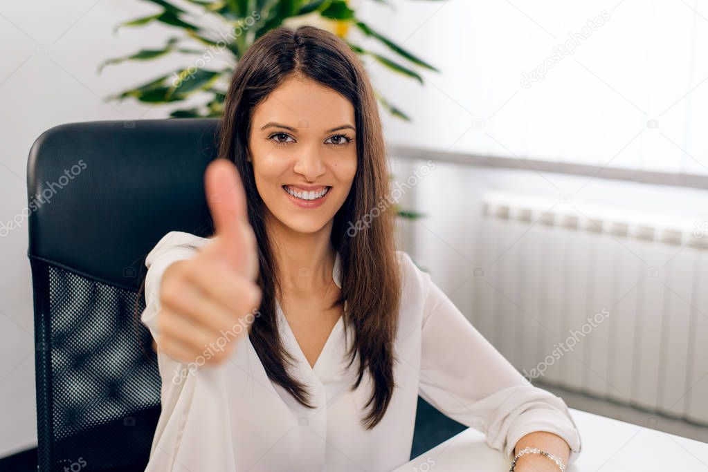 Smiling successful woman giving a thumbs up